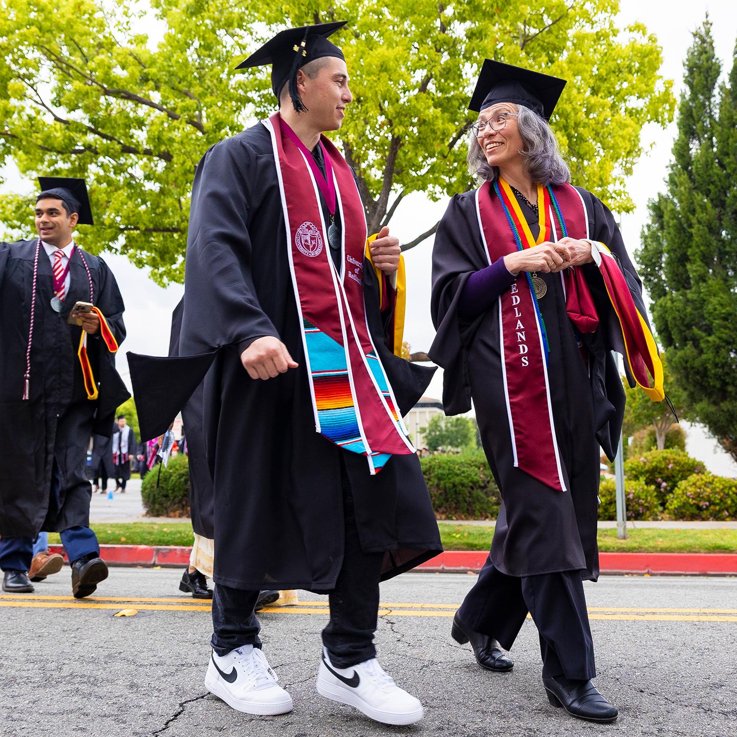 a group of people in graduation gowns and caps walking down the street