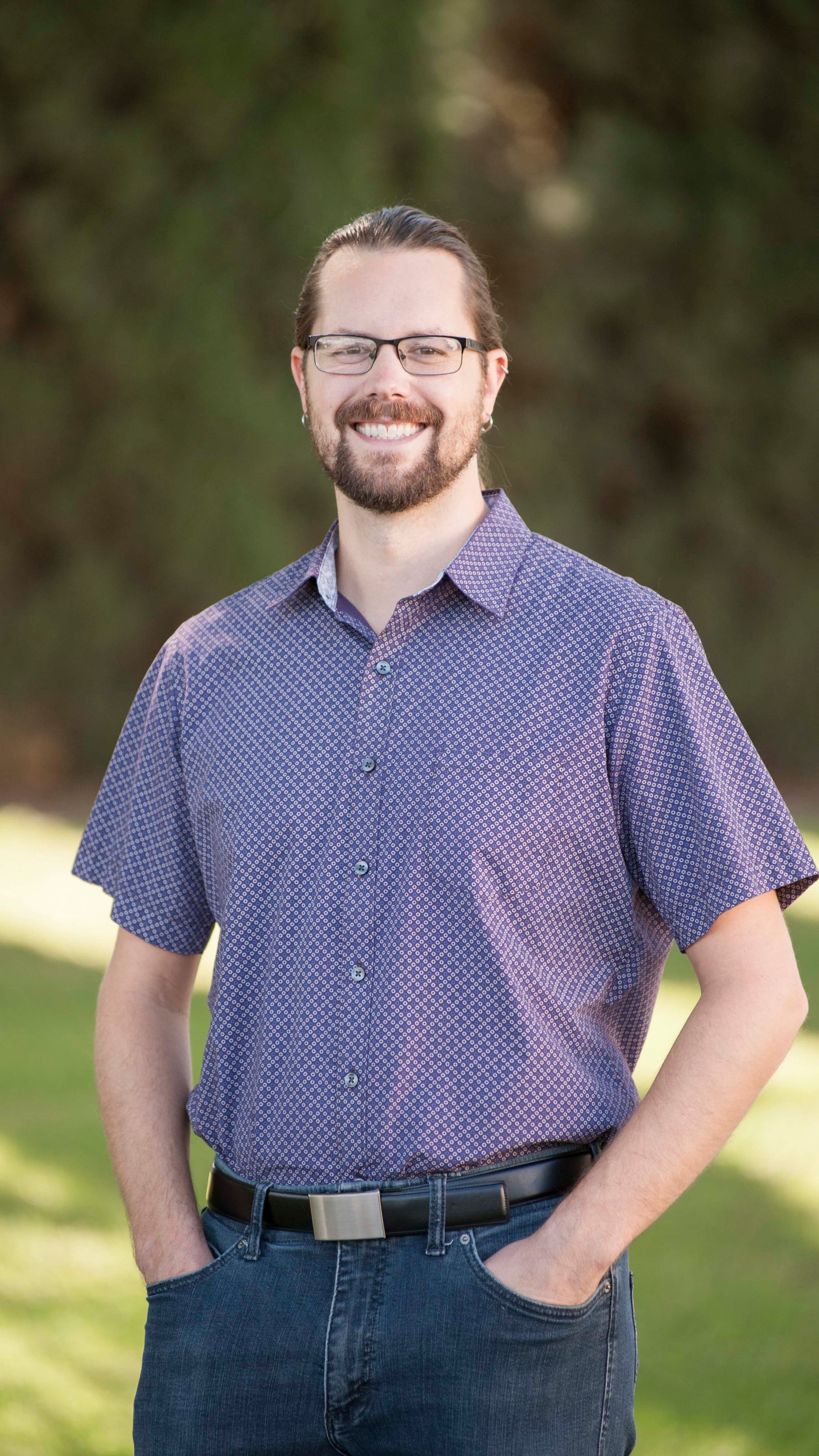 a man with glasses and a beard wearing a blue shirt