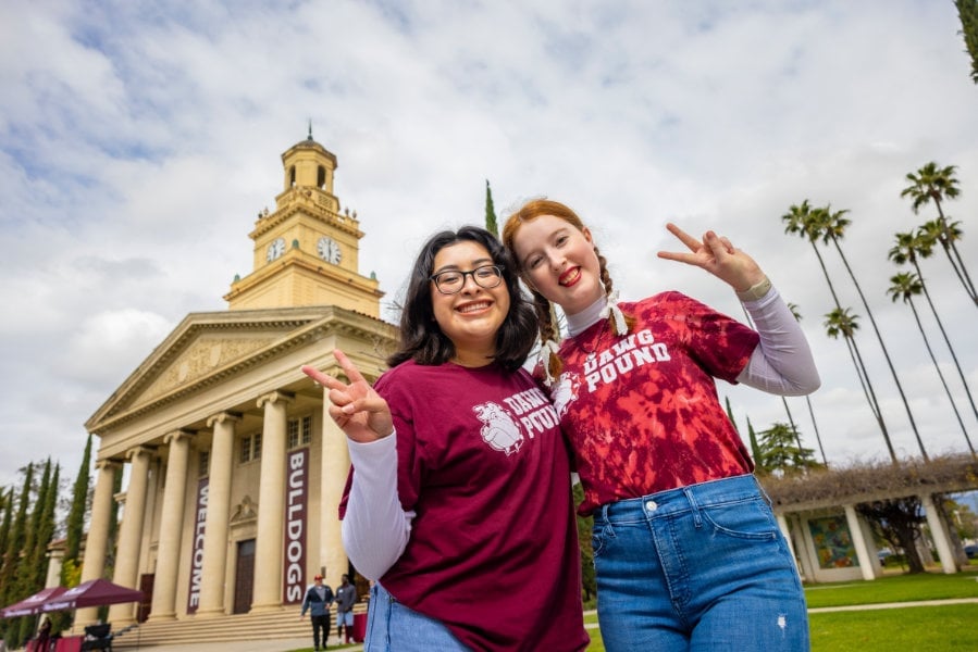 two women posing for a picture in front of a building