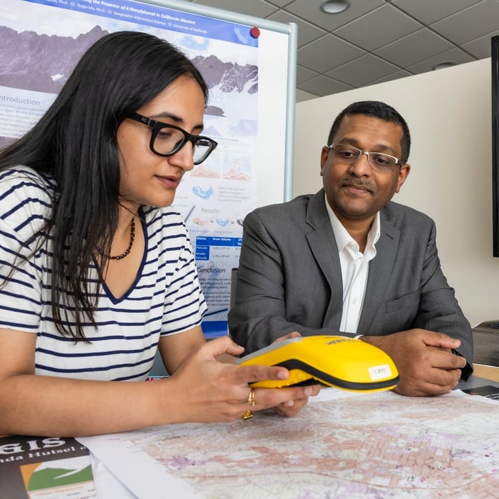 Instructor and student talking with map visual displaying on a TV screen.