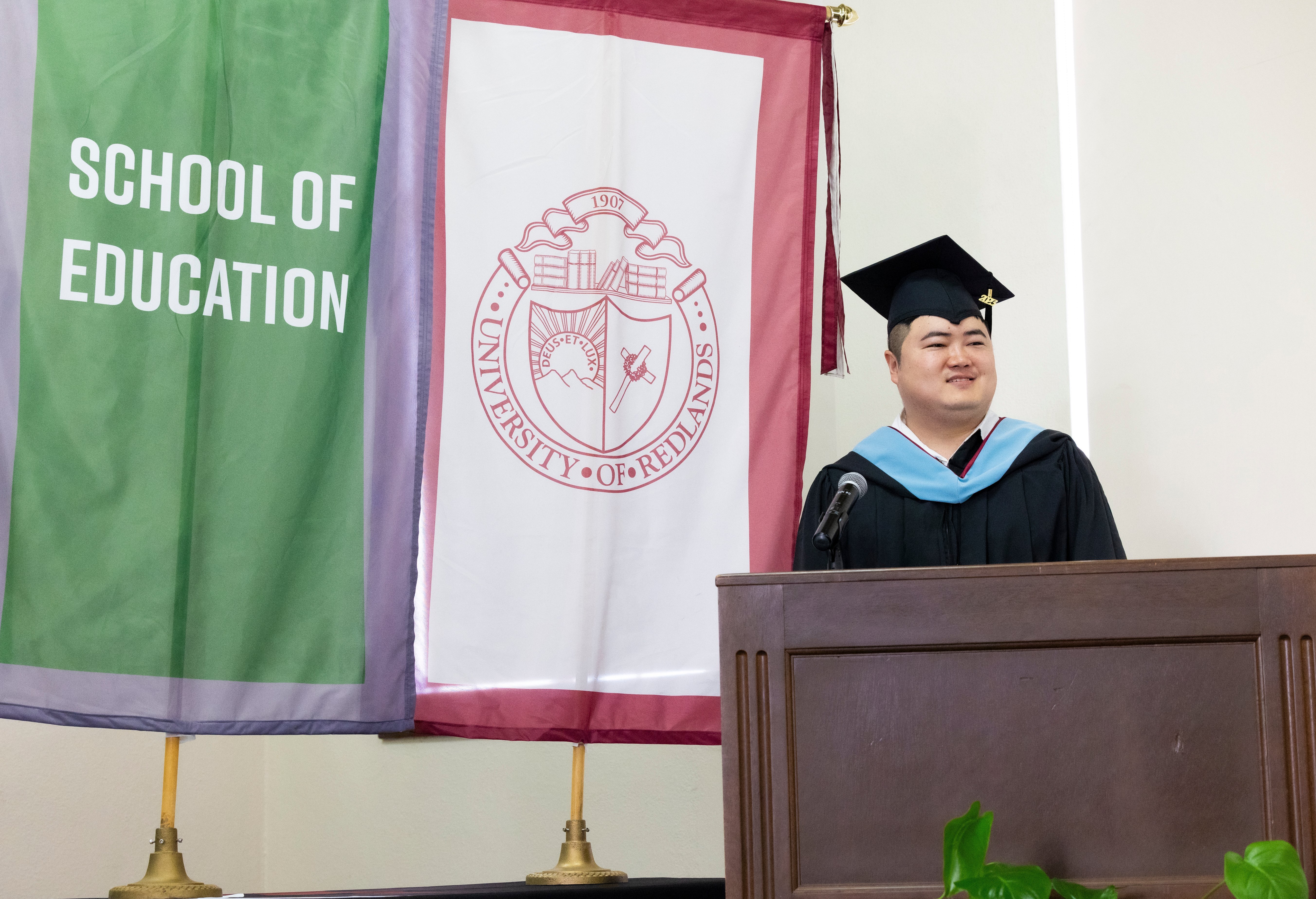 a man in a graduation cap and gown standing at a podium