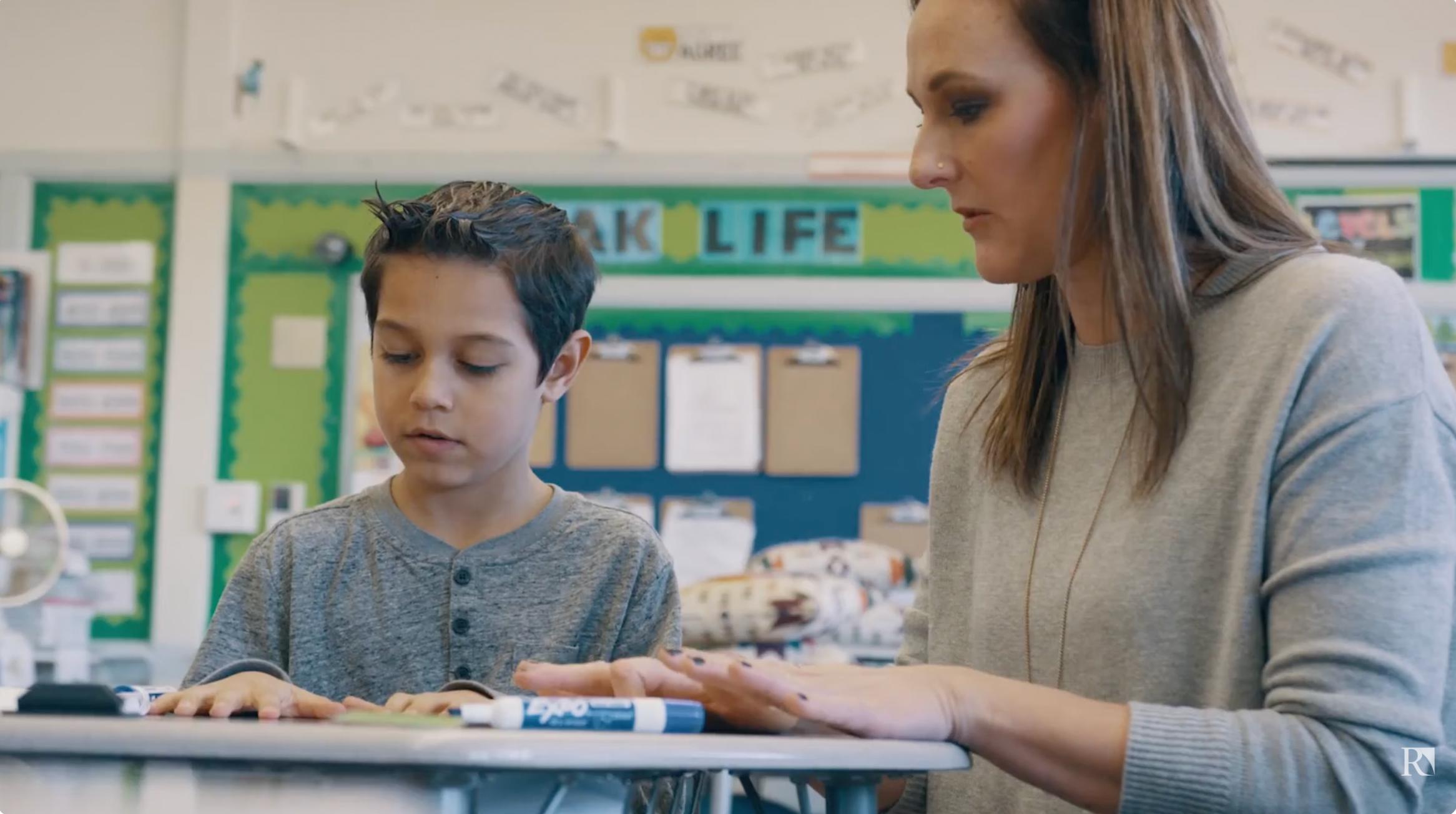 a woman and a boy sitting at a desk