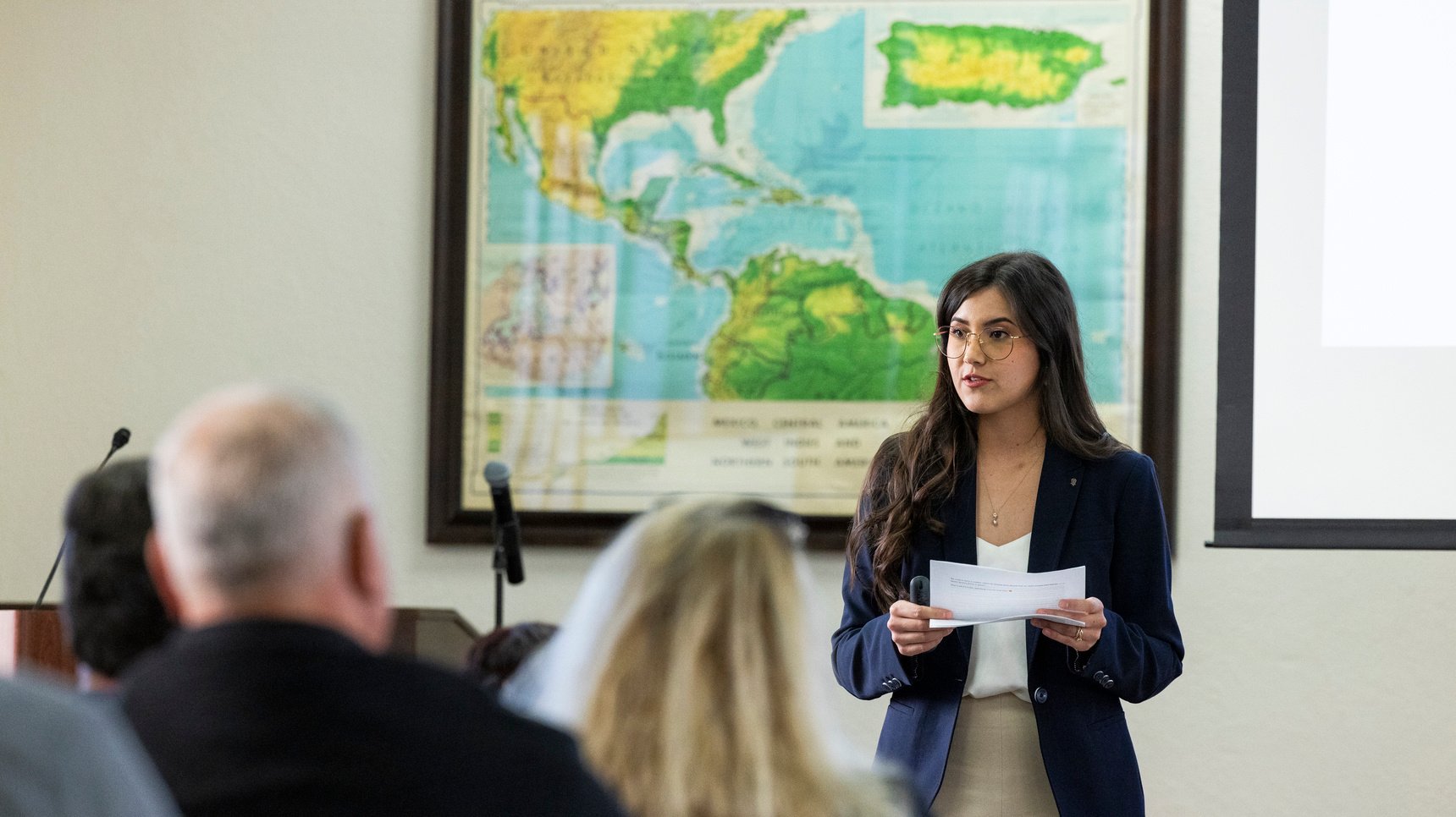 a woman holding a piece of paper in front of a group of people