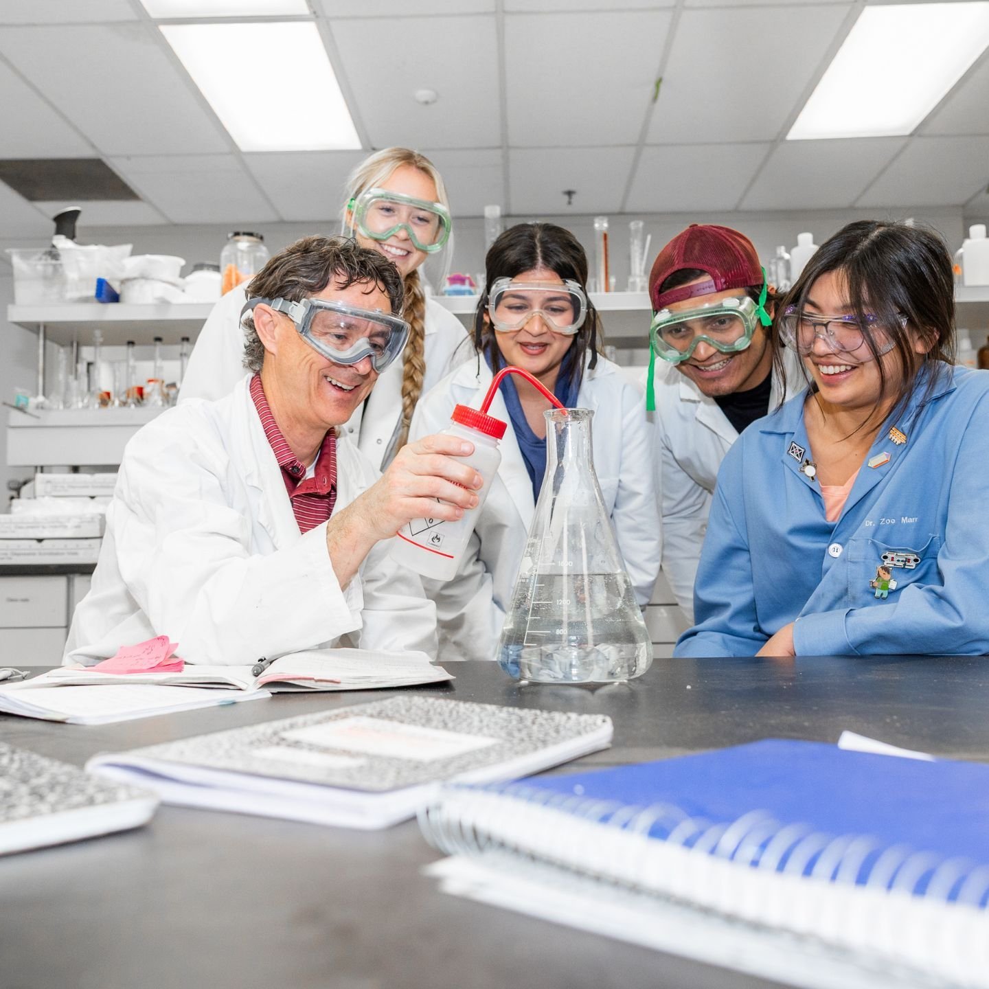 a group of people in white coats and goggles in a laboratory