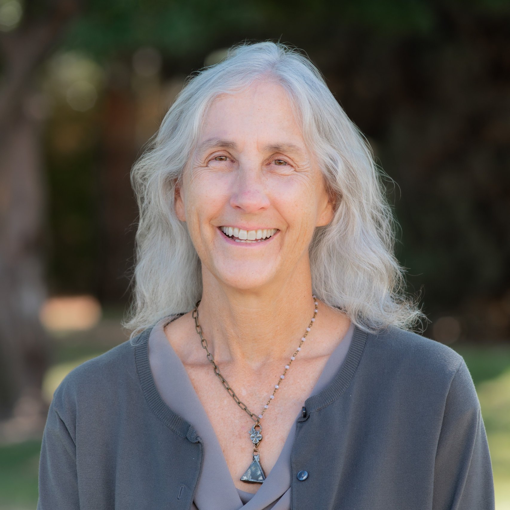 a person with long gray hair smiling