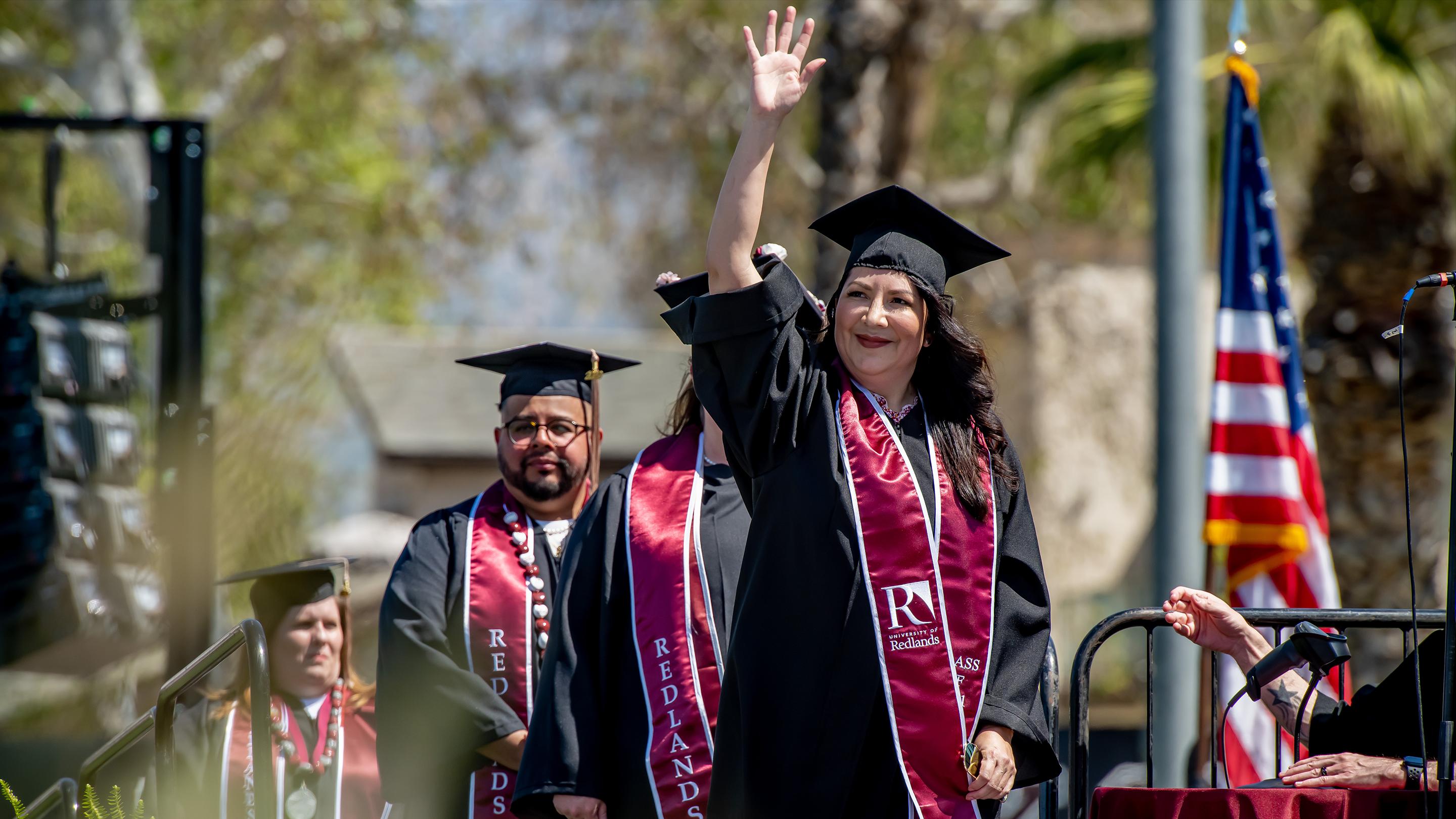 a woman in a graduation gown waving