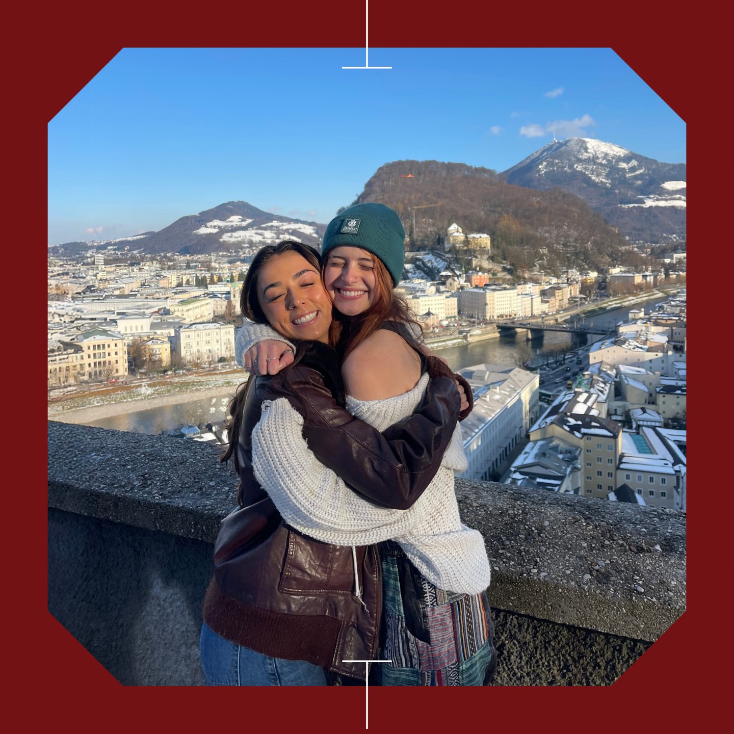 two women hugging each other on a ledge