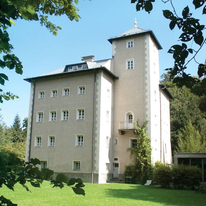 a large building with a lawn and trees in the background with Longthorpe Tower in the background