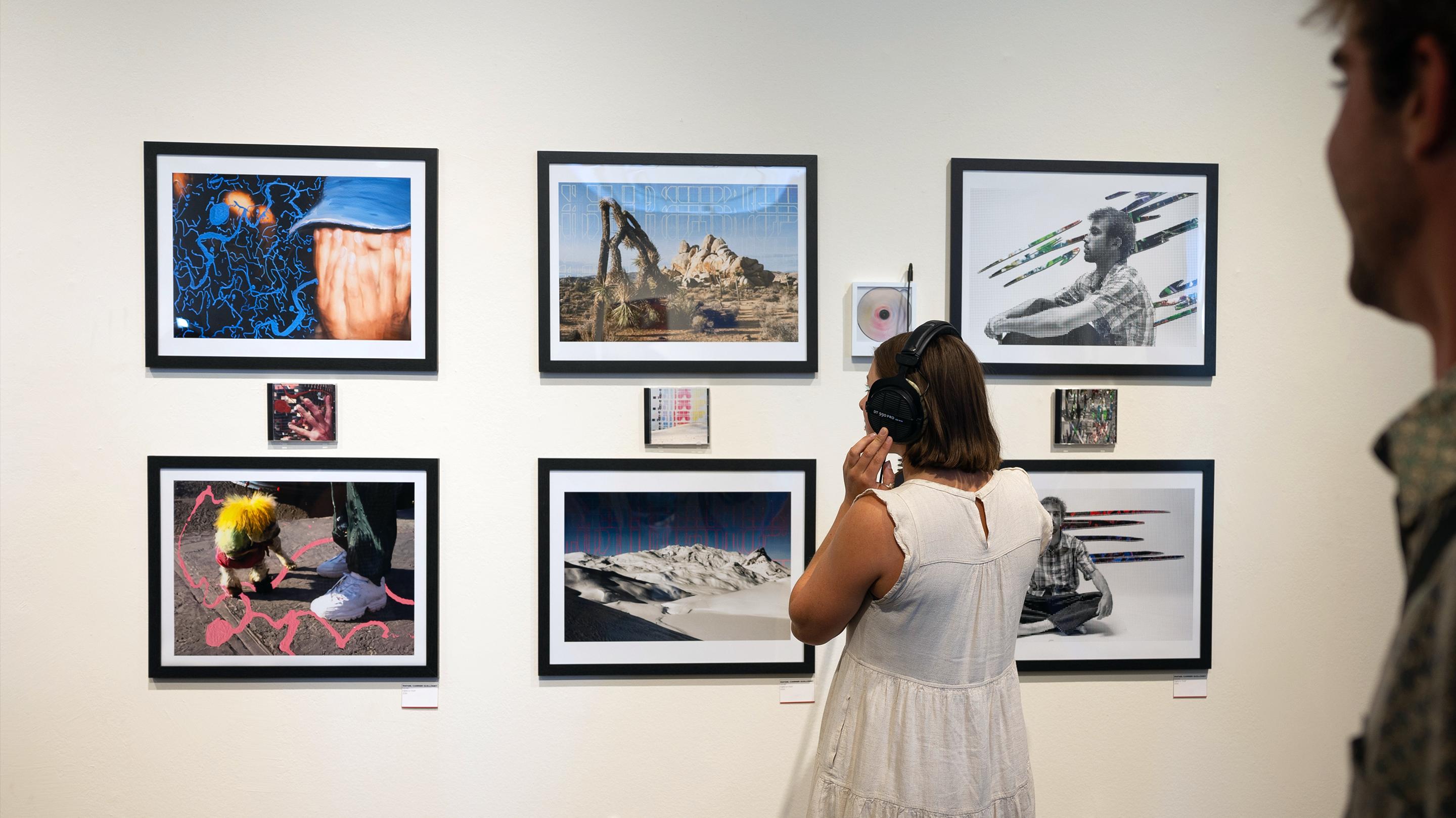 a woman wearing headphones looking at pictures on a wall
