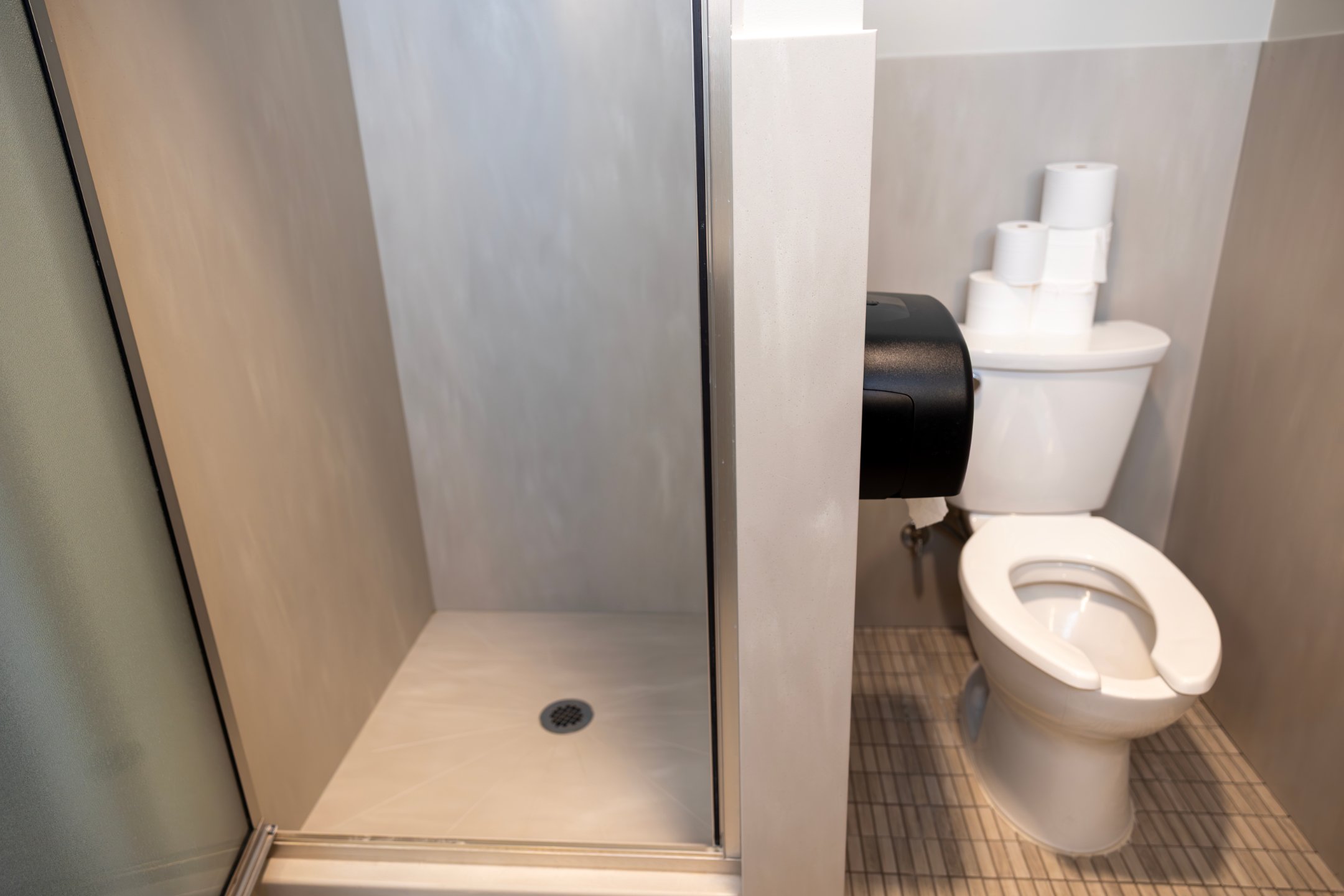 a shower stall with a toilet and toilet paper roll