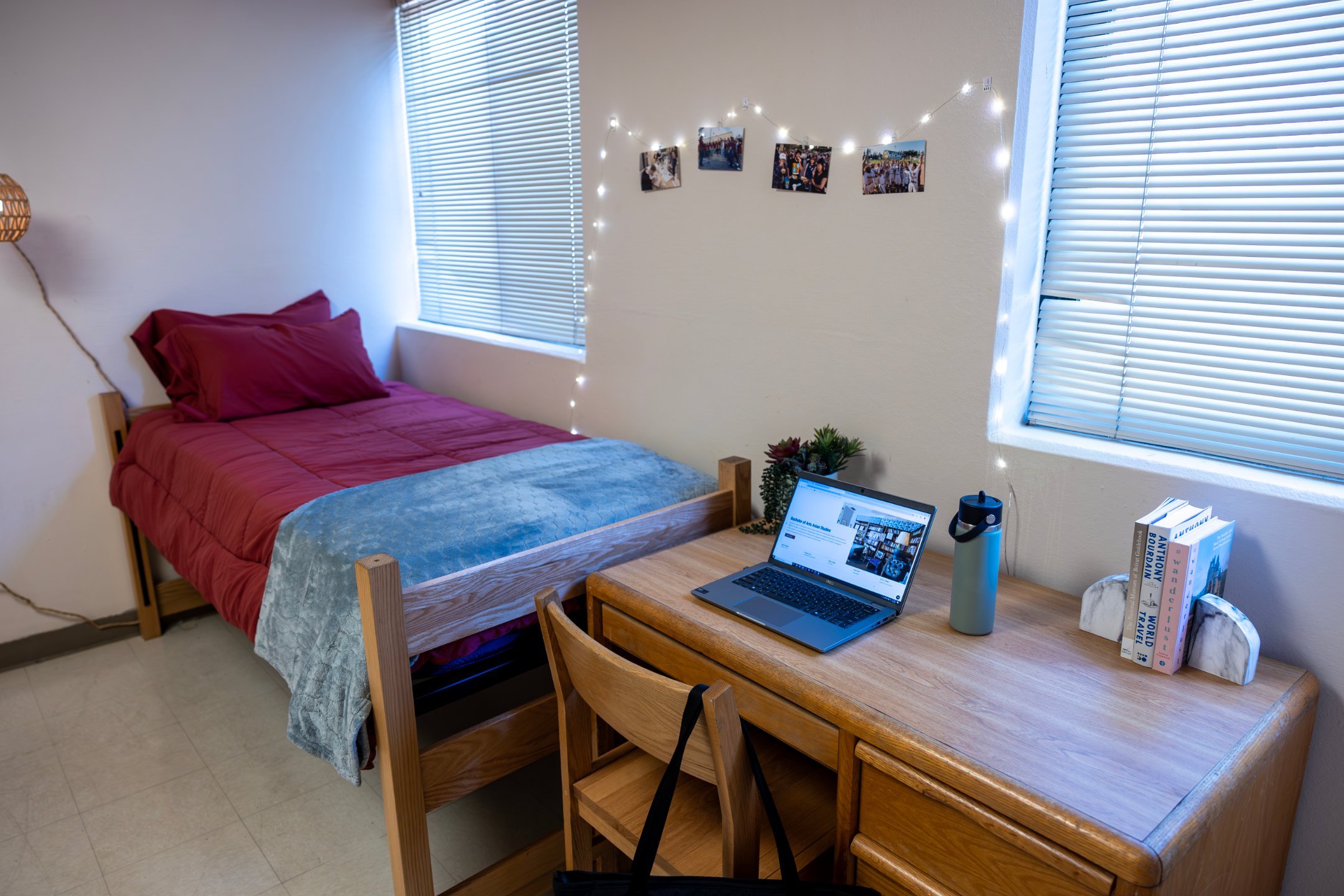 a laptop on a desk next to a bed