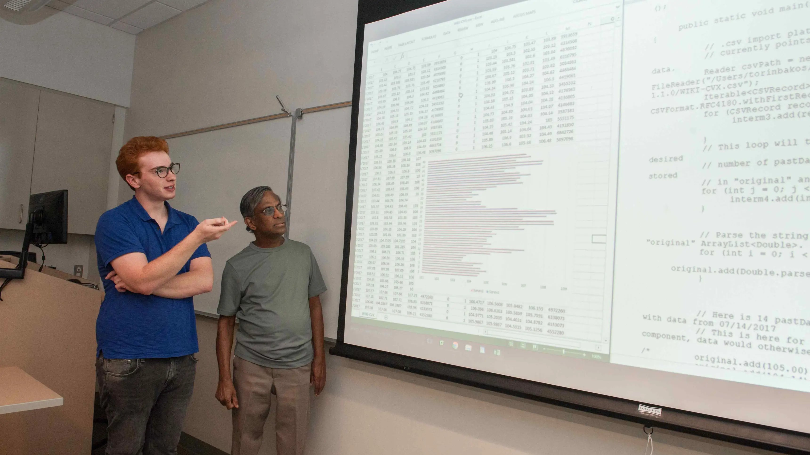 a man standing next to a large screen