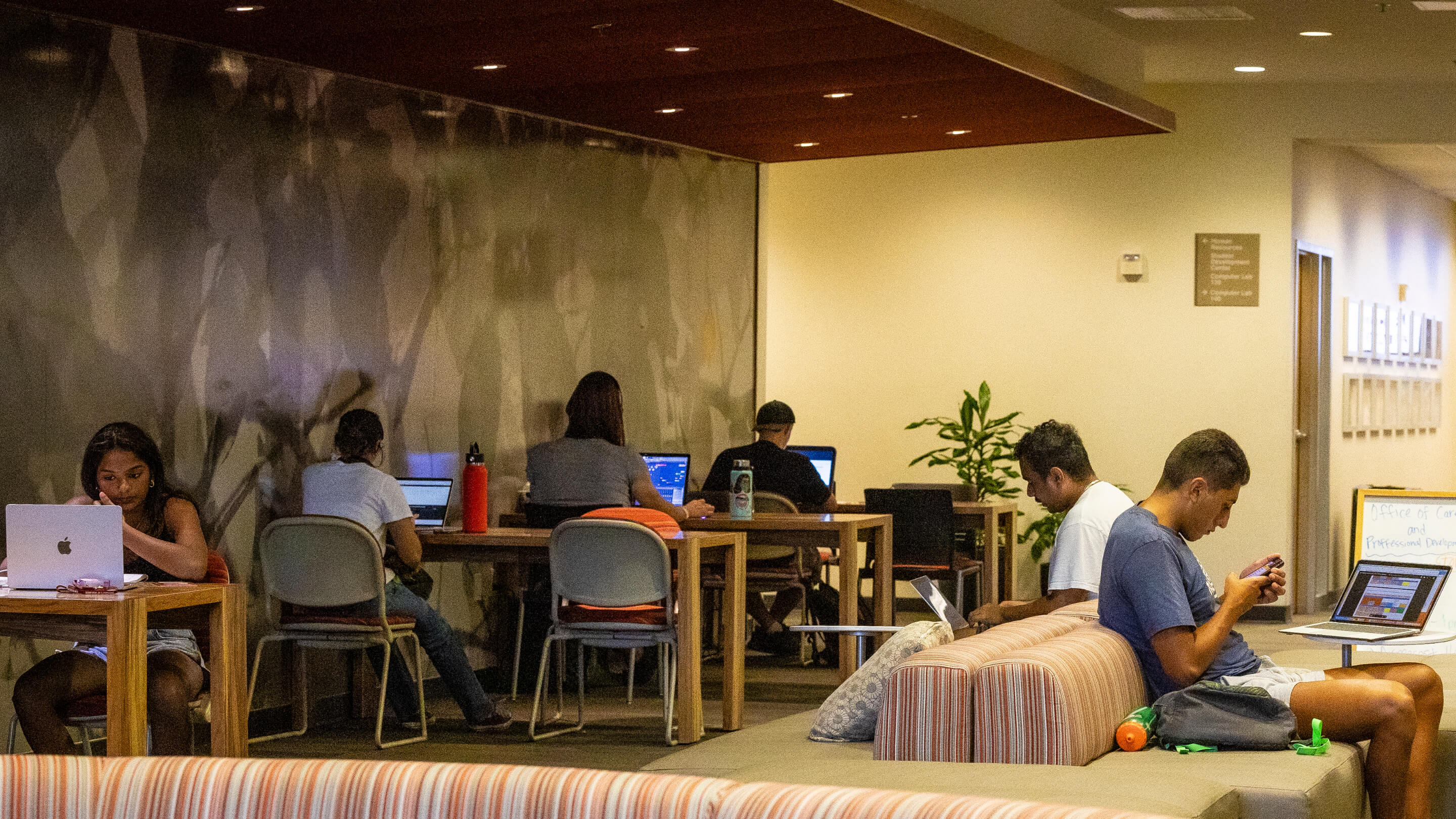 a group of people sitting at a table with laptops