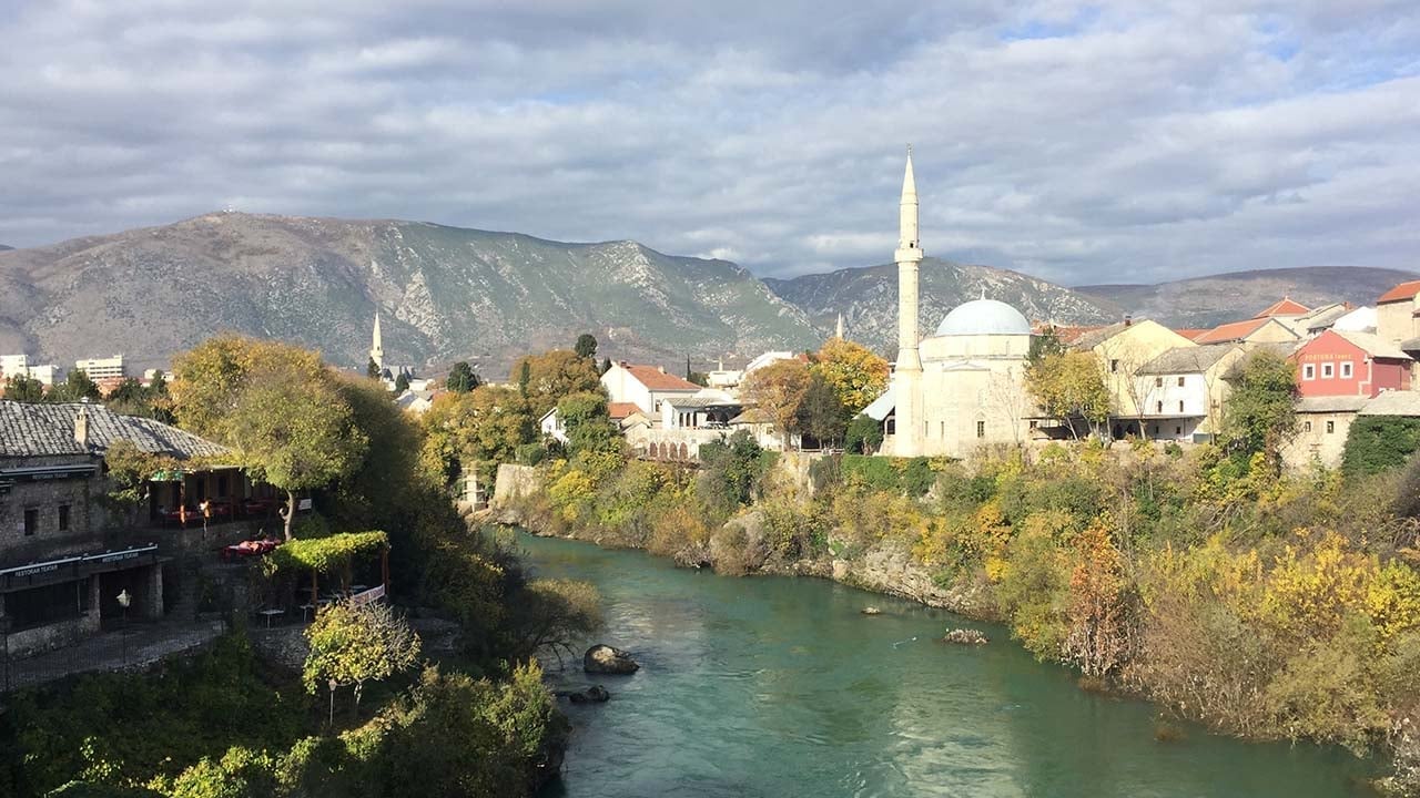 a river with a building and mountains in the background