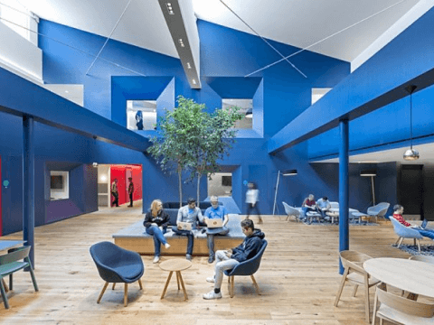 people sitting in a room with blue walls and a tree