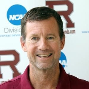 a man smiling in front of a sign