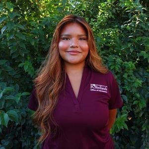 a woman standing in front of bushes