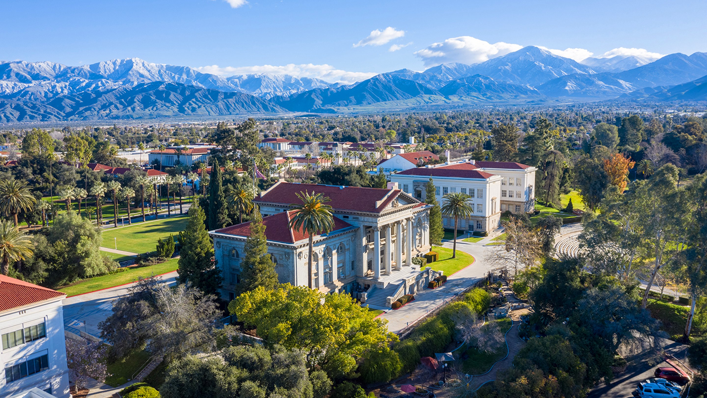 a large building with trees and mountains in the background