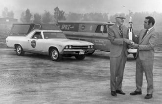 a man holding a rocket next to a couple of cars