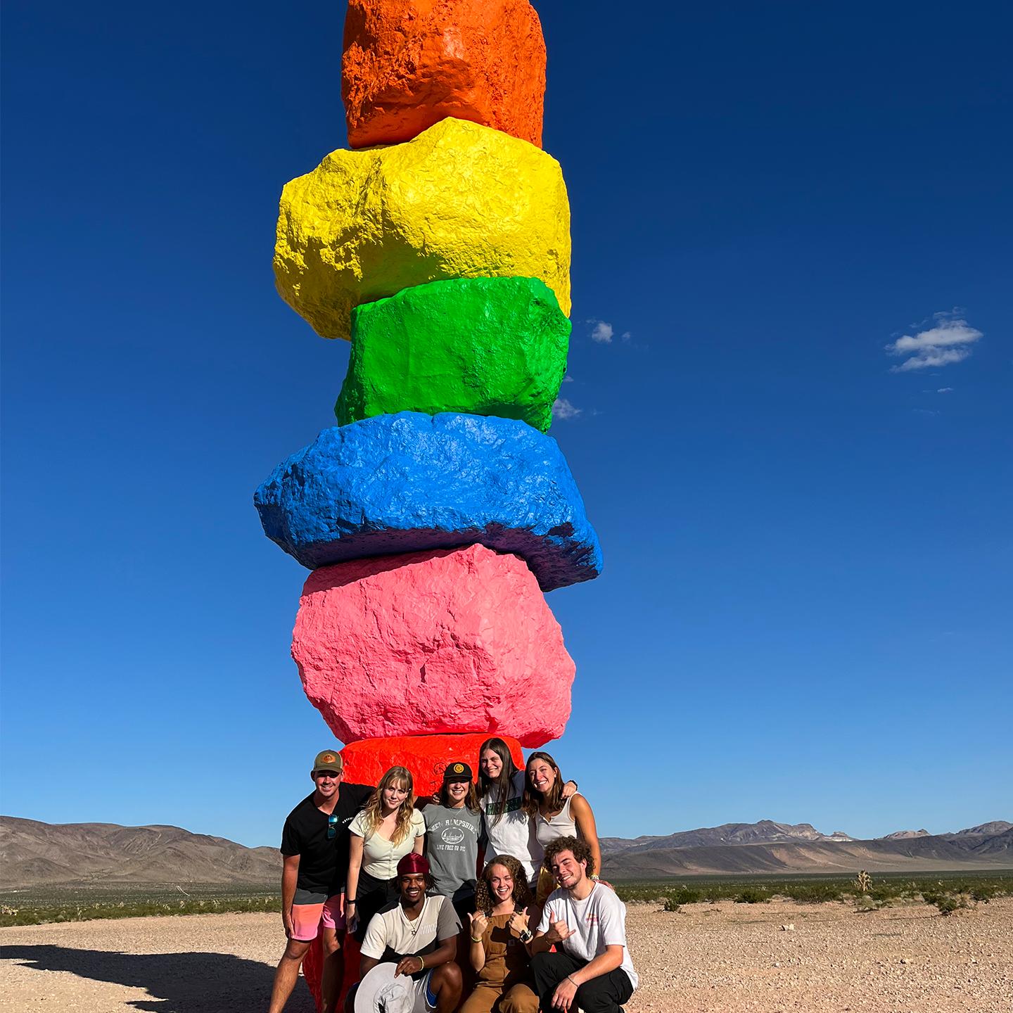 a group of people posing with a stack of colorful rocks