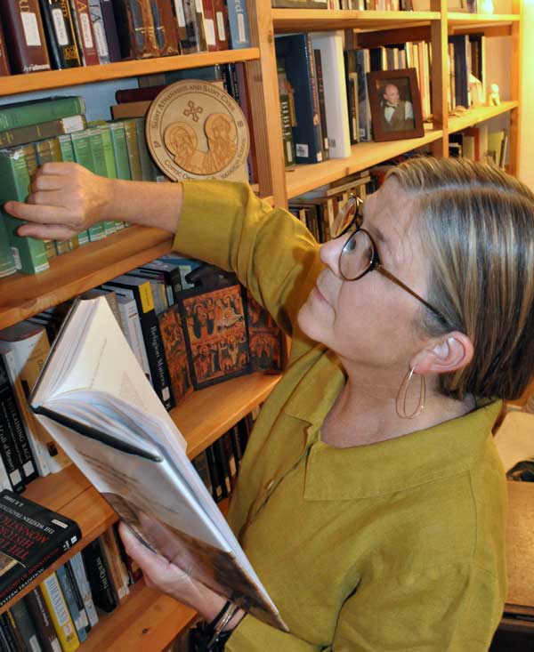 Lillian Larsen in her study looking through the books on her shelf.