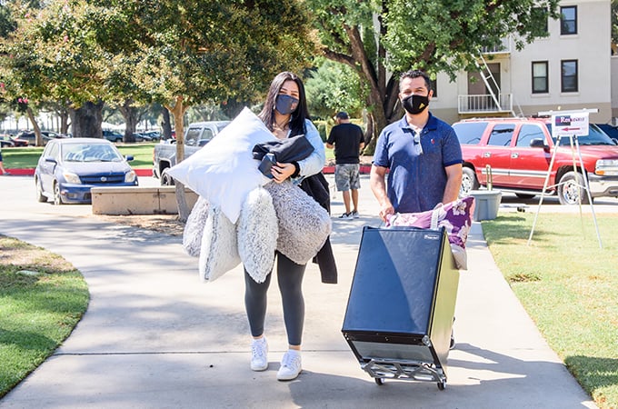 A student moves belongings into her residence hall, with help from family members and friends.
