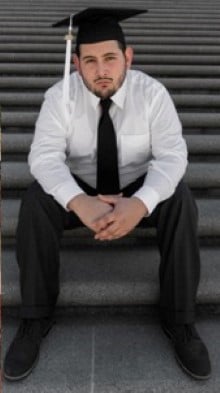 Javier Garcia III seated on outdoor steps wearing formal attire and a graduation cap.