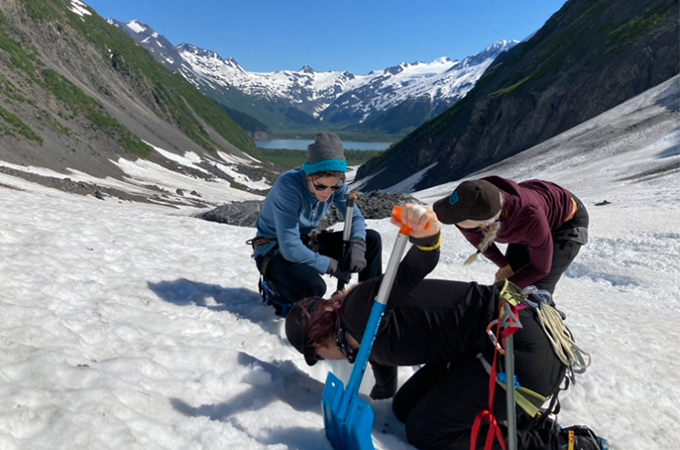Three people perform scientific research on a glacier in Alaska.