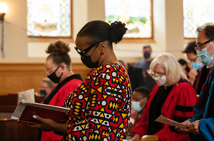 A group of people stand in a sanctuary and look at hymnals.