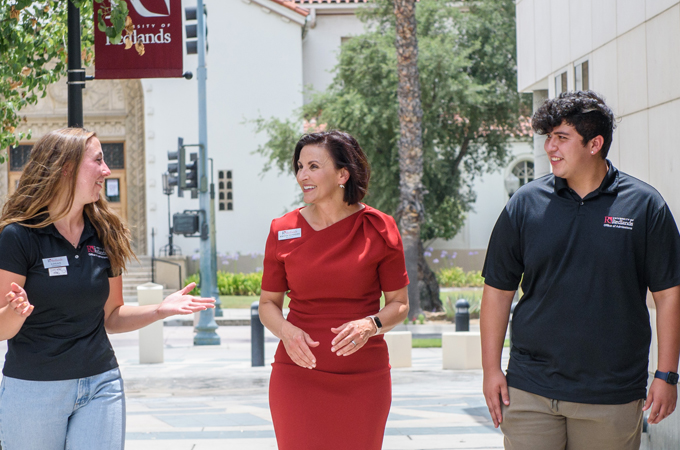 President Newkirk walks through Hunsaker Plaza, flanked by two students.