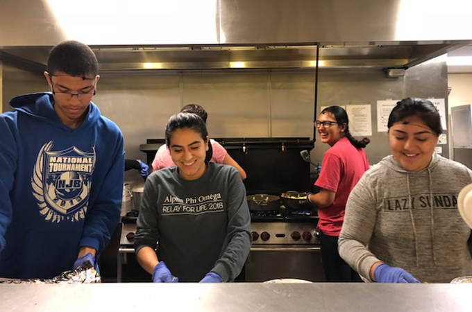University of Redlands students prepare food in a kitchen.