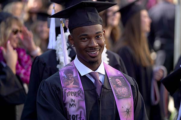 black male student smiling during CAS commencement ceremony in cap and gown