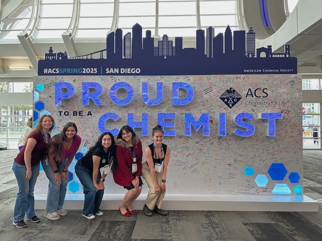a group of women posing in front of a sign