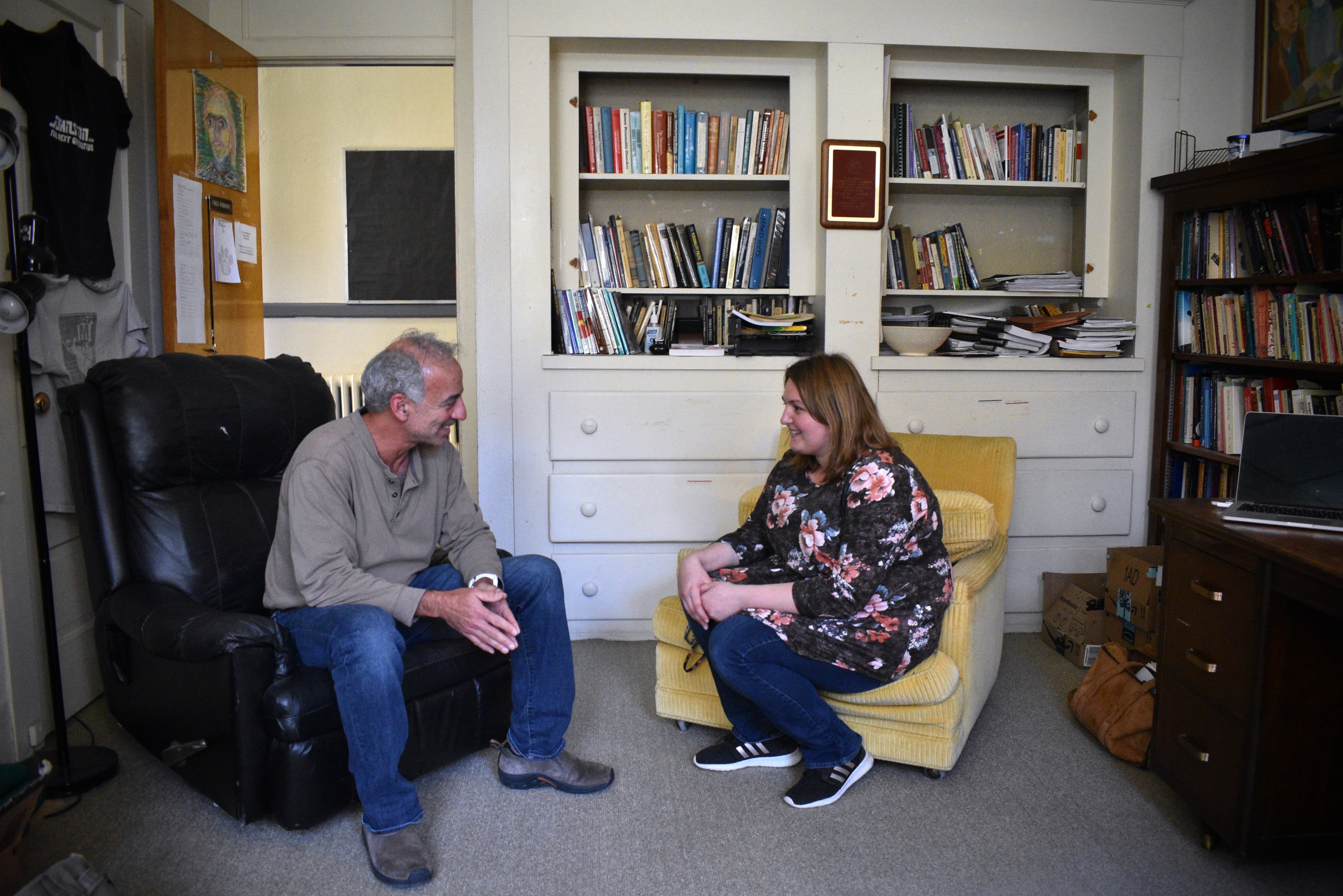a man and woman sitting in chairs and talking