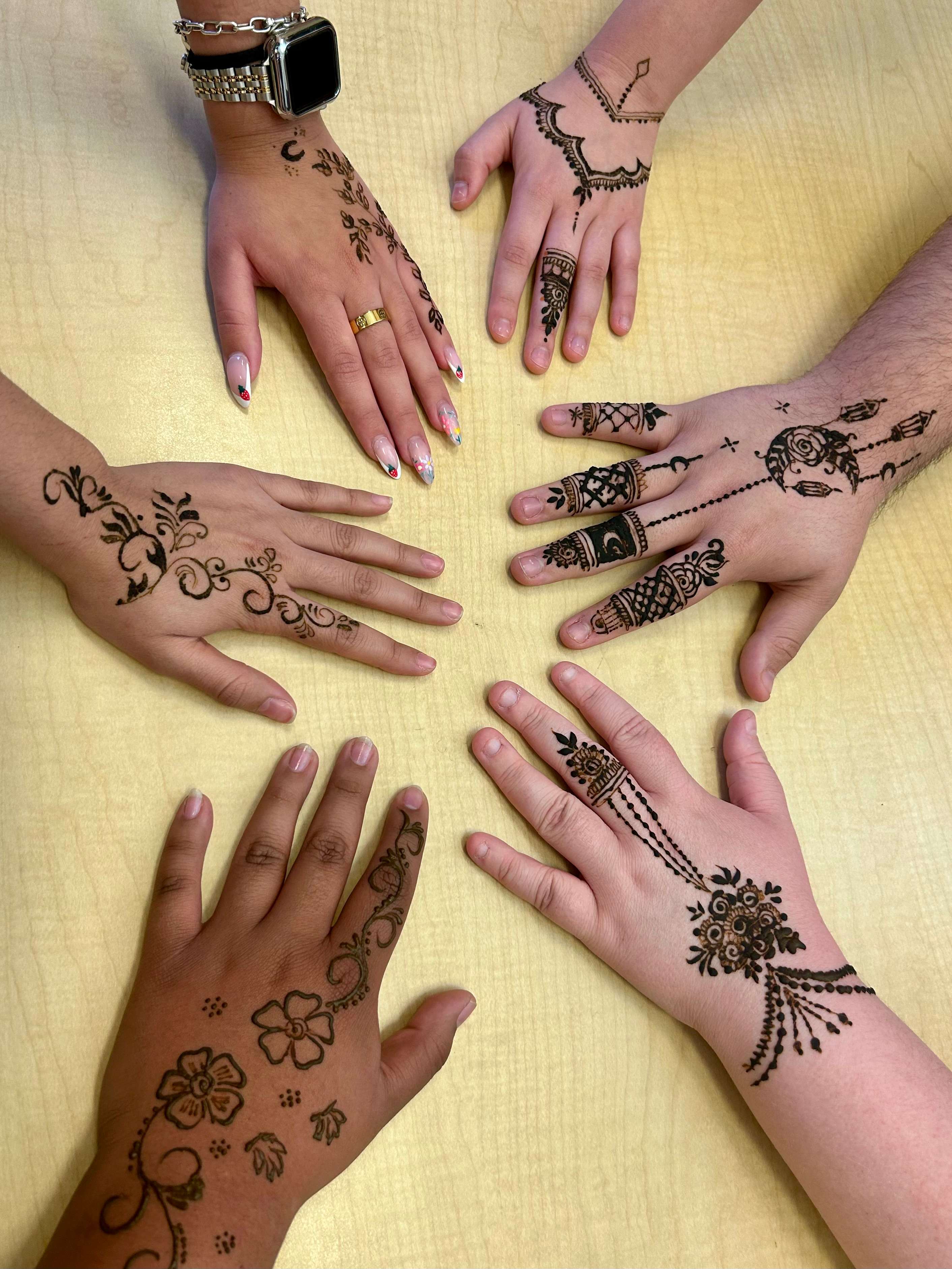 a group of hands with henna designs on them