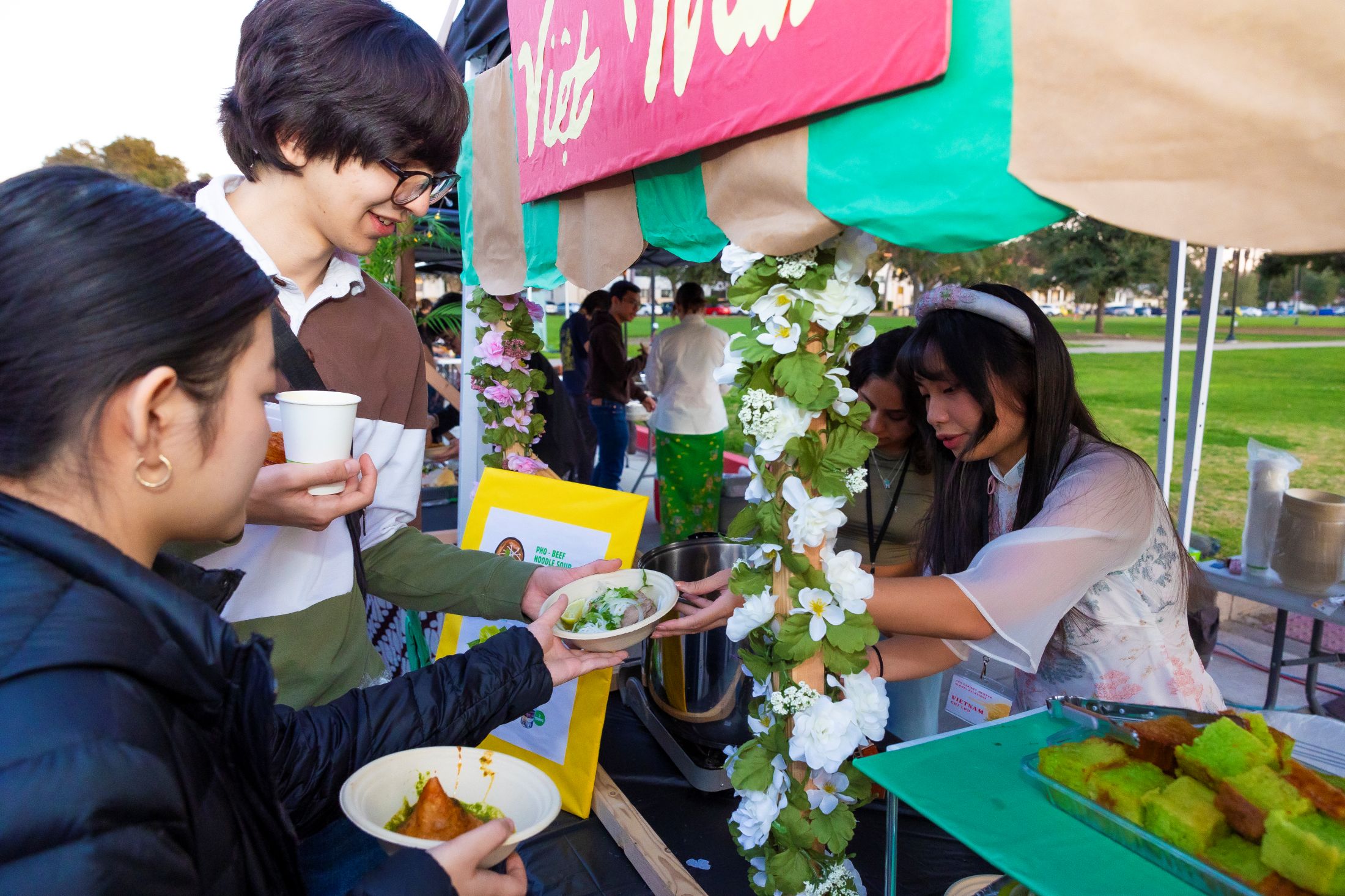 Students serve and purchase food from a decorated booth at the Asian Student Association Night Market on campus.