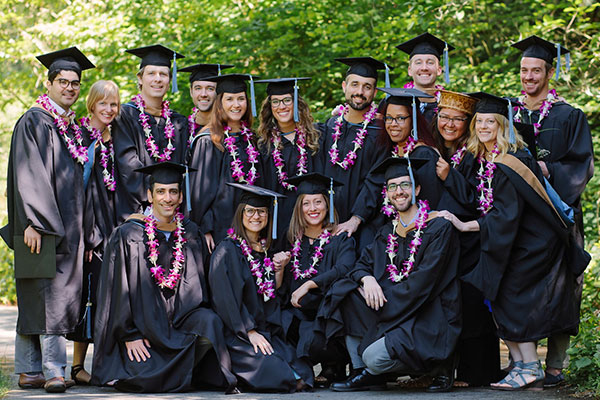 A group of Presidio grads outside in front of green foliage.