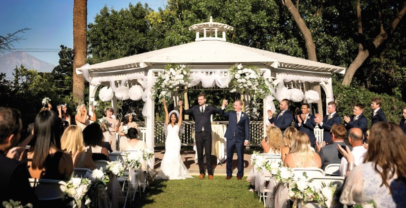 Wedding party and guests in front of white gazebo