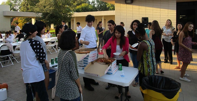 Truesdail students and Japanese student visitors eat pizza